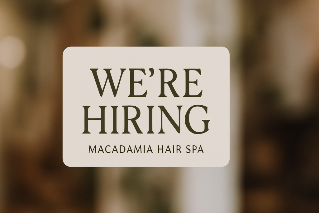 A sign reads Were Hiring at Macadamia Hair Spa, a hair salon recruiting in Widnes, against a blurred brown background.