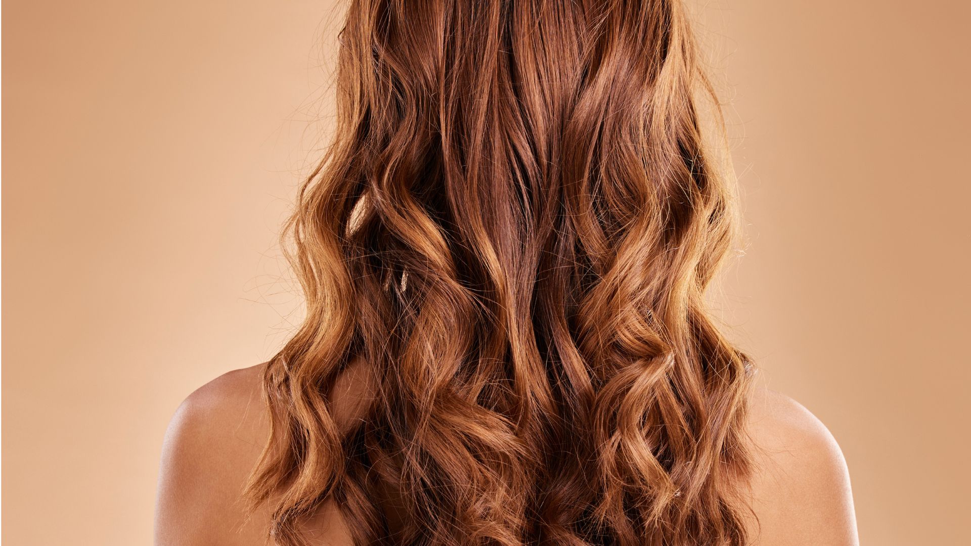 A person with long, wavy, light brown hair is seen from behind against a light beige background, creating a sense of calm and stress relief.