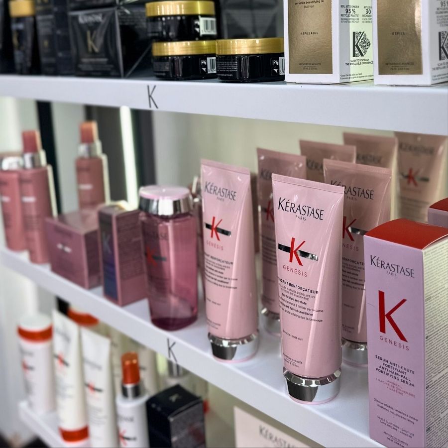 Shelves showcase an assortment of Kérastase Genesis hair care products, such as shampoo, conditioner, bottles, and jars, all neatly arranged by type.
