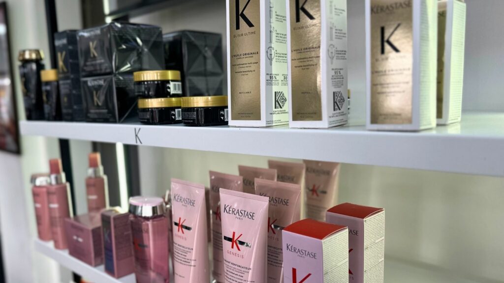 Shelves at the Kérastase Salon displaying an array of Kérastase hair care products, with bottles and boxes in black, gold, pink, and red packaging.