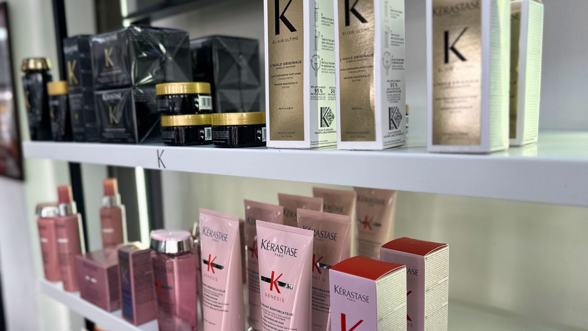 Shelves at the Kérastase Salon displaying an array of Kérastase hair care products, with bottles and boxes in black, gold, pink, and red packaging.