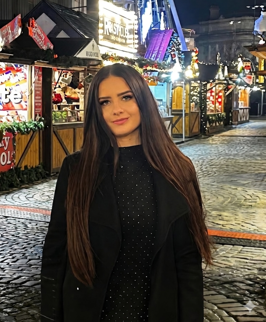 A woman with long brown hair stands on a cobbled street at night, with festive market stalls and Christmas lights glowing in the background.